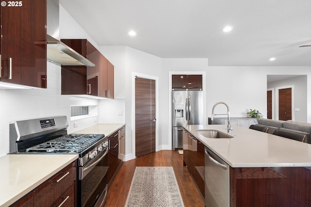 kitchen with wall chimney range hood, appliances with stainless steel finishes, modern cabinets, a sink, and light countertops