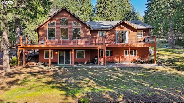 rear view of property featuring a yard, a wooden deck, and a patio area