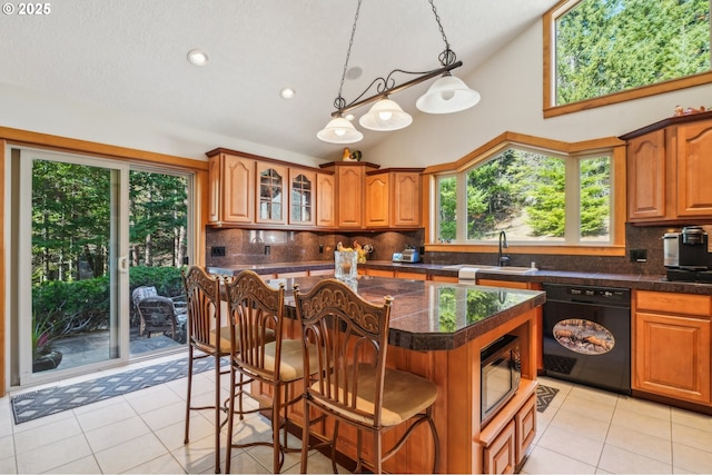 kitchen with black appliances, a breakfast bar, brown cabinetry, and a sink