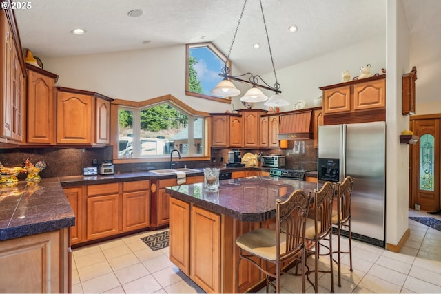 kitchen featuring stainless steel appliances, a sink, high vaulted ceiling, brown cabinetry, and light tile patterned flooring