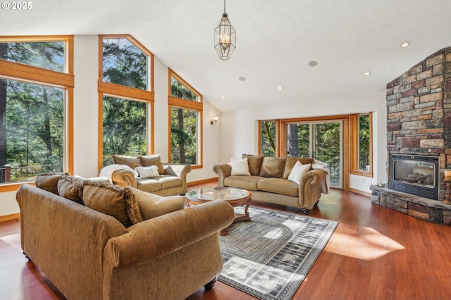 living area featuring recessed lighting, a stone fireplace, wood finished floors, high vaulted ceiling, and baseboards