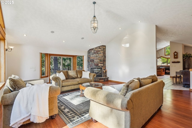 living room with a textured ceiling, high vaulted ceiling, recessed lighting, a large fireplace, and wood finished floors