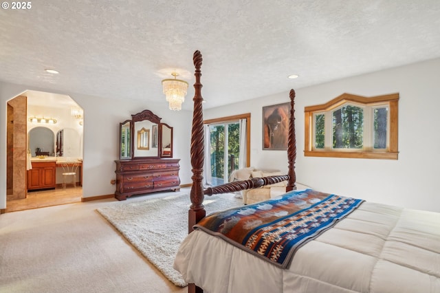 bedroom with arched walkways, a textured ceiling, ensuite bathroom, light colored carpet, and baseboards