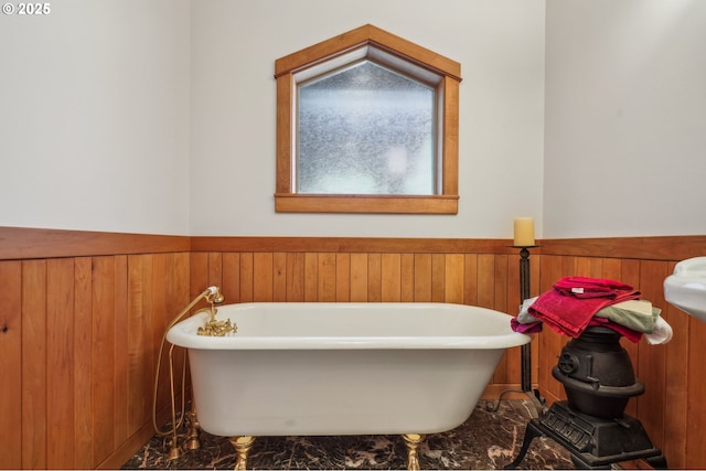 bathroom with a wainscoted wall, a freestanding tub, and wooden walls