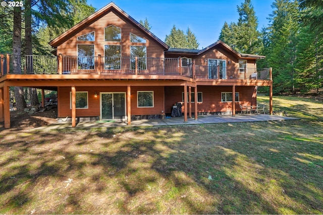 back of property featuring a wooden deck, a lawn, and a patio