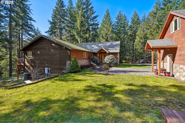 rear view of house with stone siding, a yard, and central air condition unit