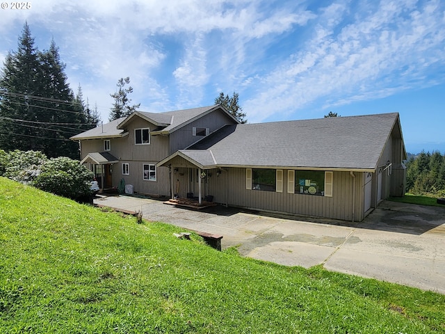 view of front of house featuring a shingled roof, a front lawn, and concrete driveway