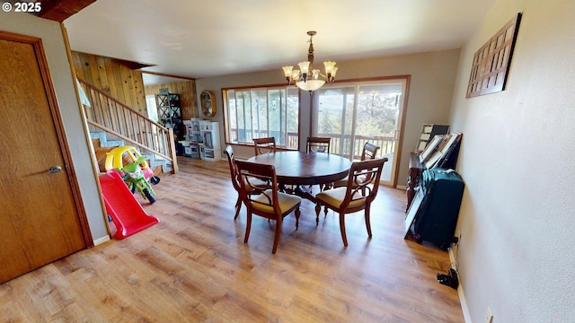 dining space with a healthy amount of sunlight, light wood-style floors, stairs, and a chandelier