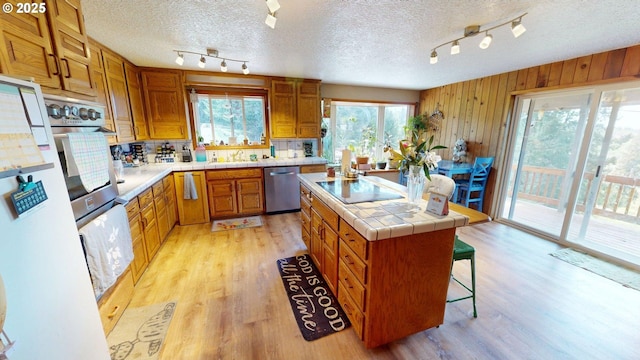 kitchen with stainless steel dishwasher, rail lighting, black electric stovetop, and a kitchen island