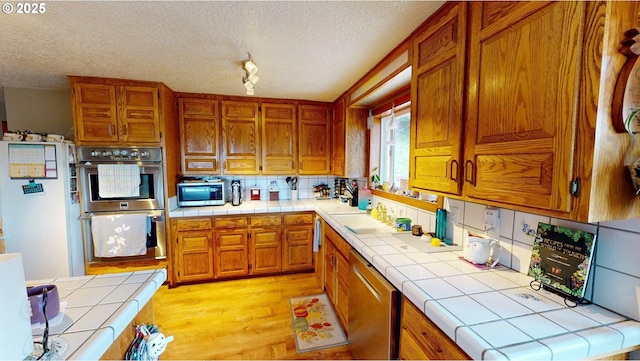 kitchen featuring tile countertops, a textured ceiling, and stainless steel appliances