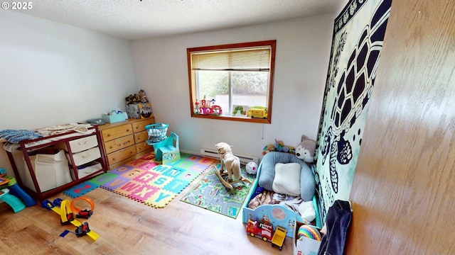 rec room with wood finished floors and a baseboard radiator
