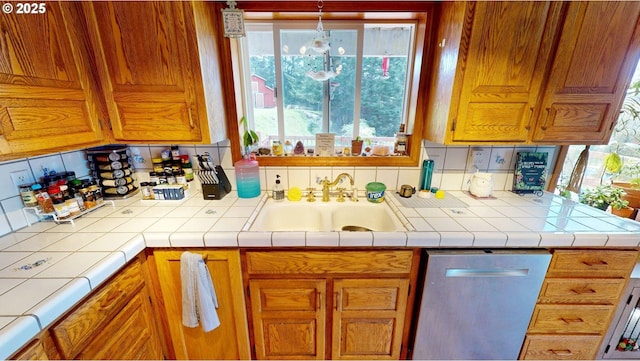 kitchen featuring a sink, a healthy amount of sunlight, brown cabinets, and dishwasher