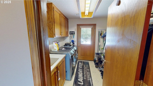 washroom with a textured ceiling, cabinet space, and washing machine and clothes dryer