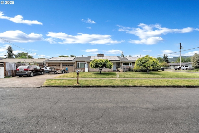 ranch-style home featuring solar panels, a front yard, asphalt driveway, and an attached garage