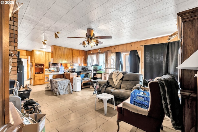 living area featuring wood walls and a ceiling fan