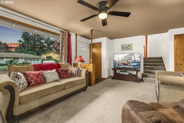 carpeted living area featuring ceiling fan, a textured ceiling, and stairway
