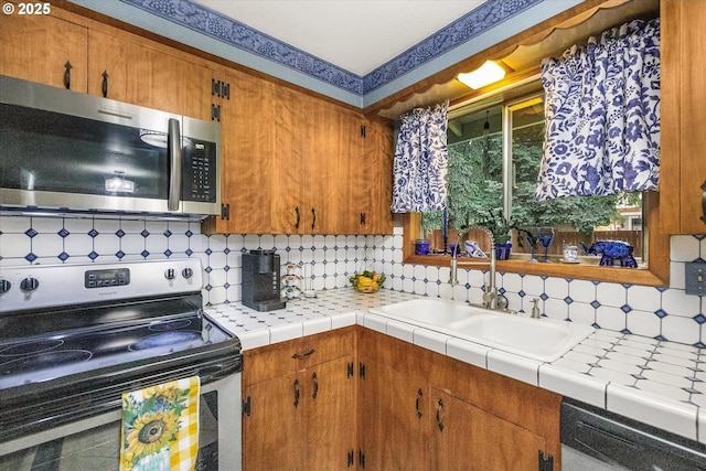 kitchen with appliances with stainless steel finishes, decorative backsplash, brown cabinets, a sink, and light countertops