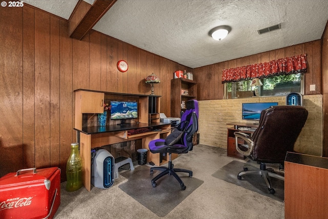 carpeted office featuring wooden walls and a textured ceiling