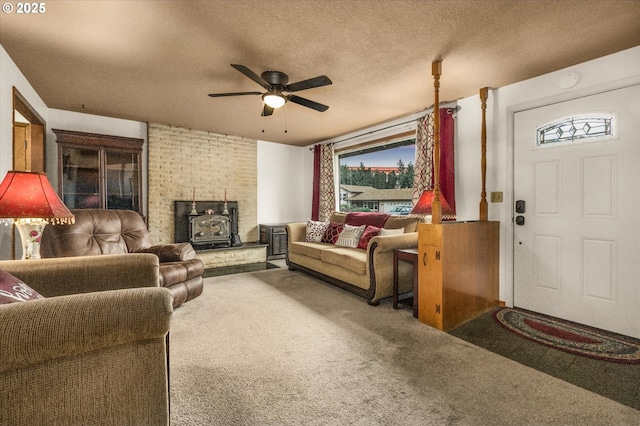 carpeted living area with a wood stove, a ceiling fan, plenty of natural light, and a textured ceiling