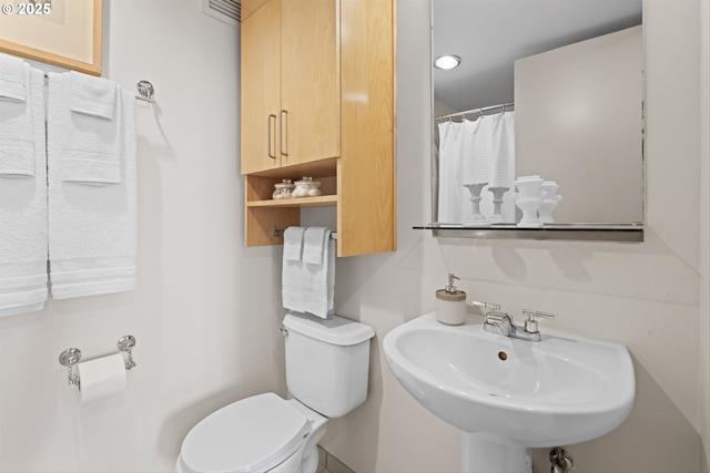 bathroom featuring a sink, a shower with curtain, and toilet