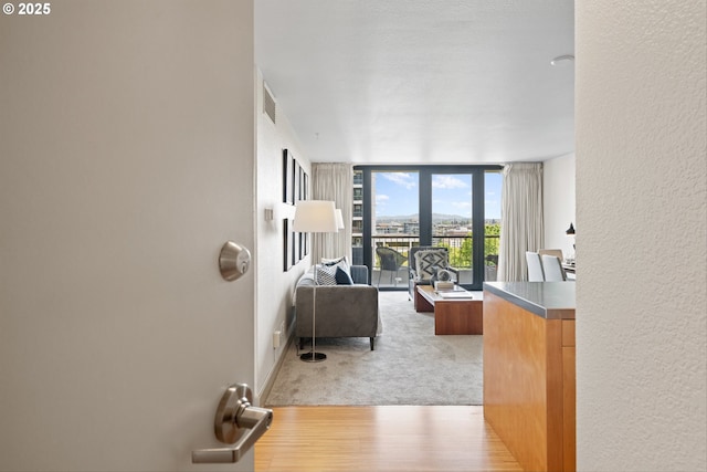 interior space featuring a wall of windows, a textured wall, light wood finished floors, and visible vents