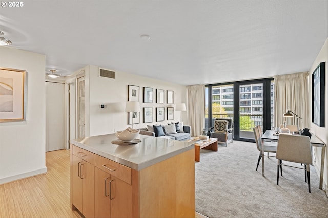 kitchen with visible vents, light brown cabinetry, stainless steel counters, a center island, and open floor plan