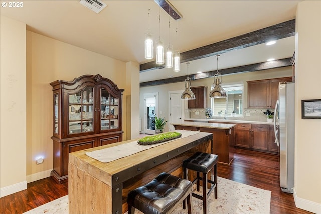 14215 SW Burlwood Ln, Beaverton, OR 97005 - kitchen with dark wood finished floors, a center island, freestanding refrigerator, decorative backsplash, and hanging light fixtures