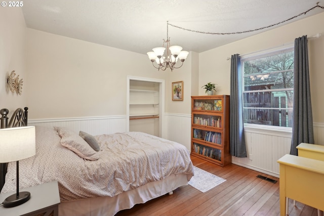 bedroom featuring hardwood / wood-style flooring, an inviting chandelier, and a textured ceiling