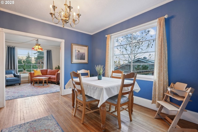 dining room with a textured ceiling, ornamental molding, light hardwood / wood-style floors, and a chandelier