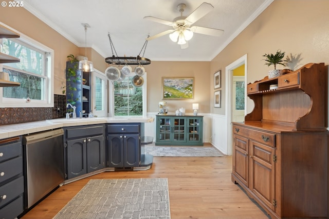 kitchen with crown molding, sink, decorative light fixtures, and dishwasher