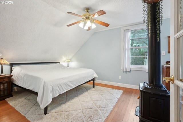 bedroom with lofted ceiling, ceiling fan, hardwood / wood-style flooring, and a textured ceiling