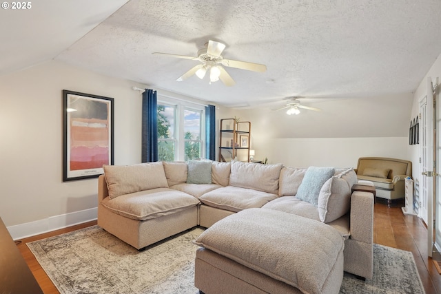 living room with ceiling fan, dark wood-type flooring, a textured ceiling, and vaulted ceiling