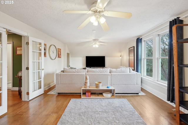 living room with french doors, vaulted ceiling, a textured ceiling, and light wood-type flooring