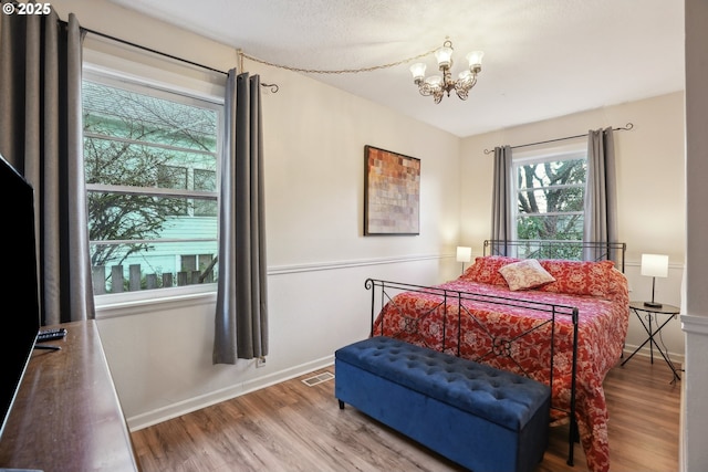 bedroom with hardwood / wood-style floors and a notable chandelier