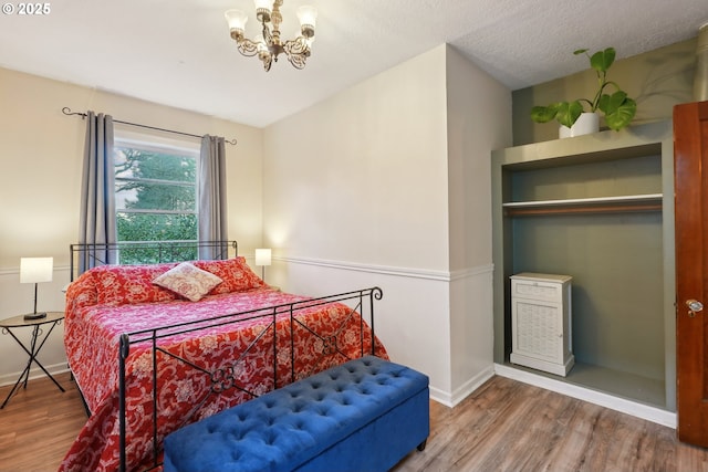 bedroom with wood-type flooring, a chandelier, and a textured ceiling