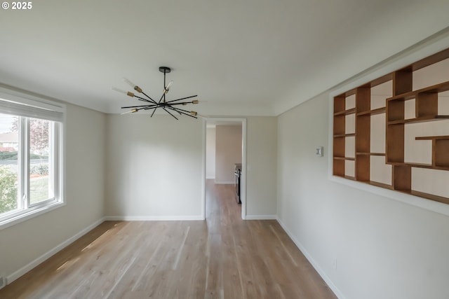 unfurnished room with baseboards, wood finished floors, and a notable chandelier