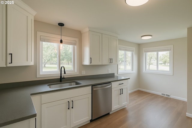 kitchen featuring dark countertops, stainless steel dishwasher, visible vents, and a sink