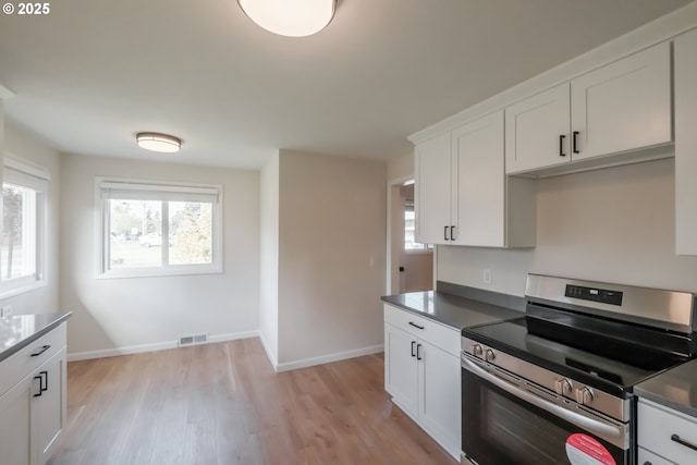 kitchen with plenty of natural light, visible vents, electric range, and light wood-style floors