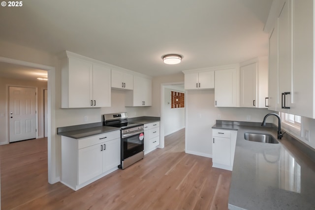 kitchen featuring baseboards, stainless steel electric range, light wood finished floors, and a sink