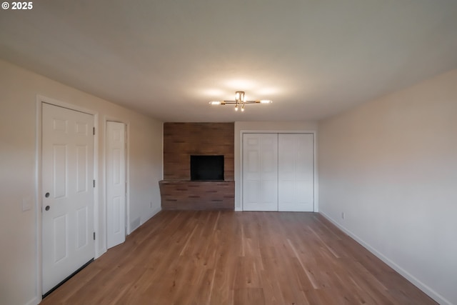 unfurnished bedroom featuring an inviting chandelier, light wood-style floors, and baseboards