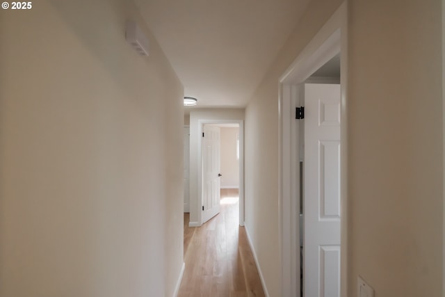 corridor with light wood-style floors and baseboards
