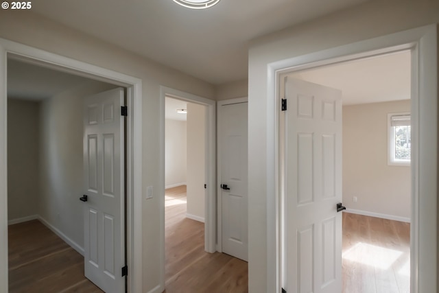 hallway featuring wood finished floors and baseboards