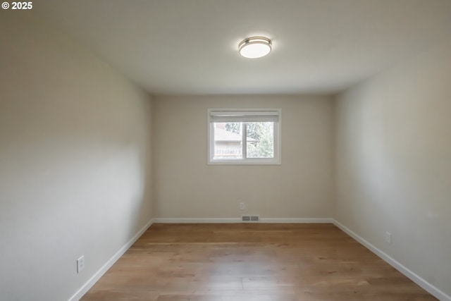 unfurnished room featuring baseboards, visible vents, and light wood finished floors