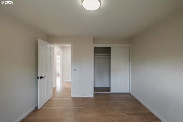 unfurnished bedroom featuring a closet, wood finished floors, and baseboards
