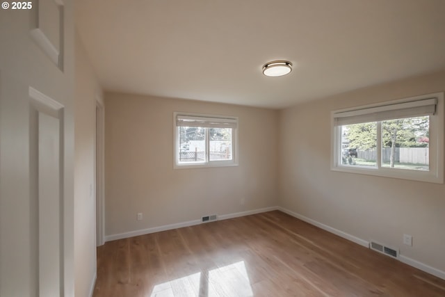 spare room featuring a wealth of natural light, visible vents, and light wood-style flooring