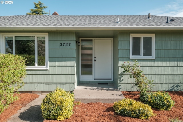 doorway to property with roof with shingles