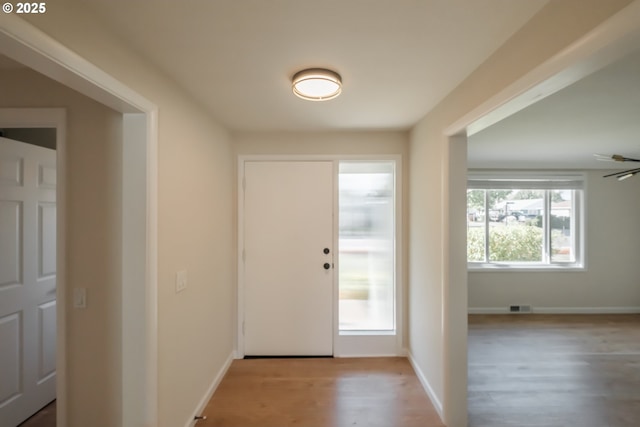 doorway with wood finished floors, visible vents, and baseboards