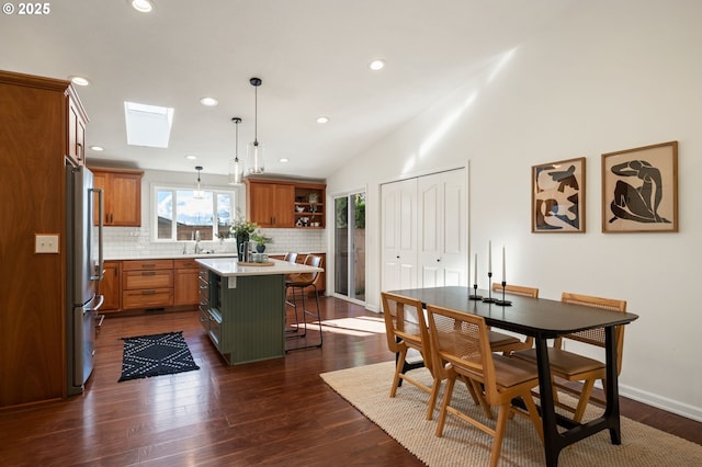 kitchen with a kitchen island, a kitchen bar, light countertops, brown cabinetry, and stainless steel fridge