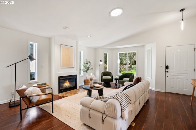 living area with baseboards, lofted ceiling, dark wood-style floors, and a fireplace with flush hearth