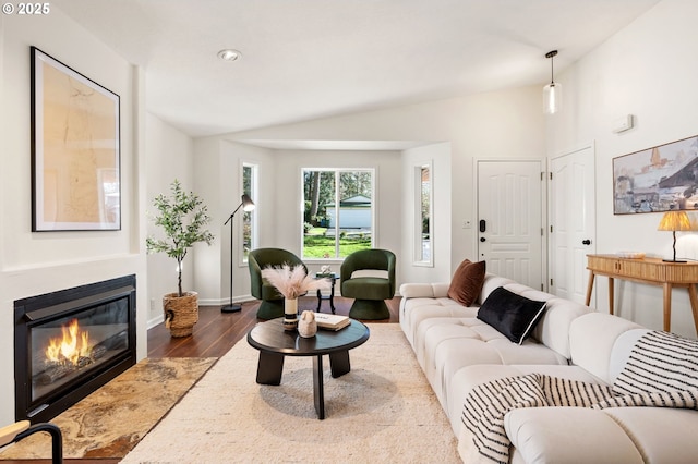 living area featuring wood finished floors, baseboards, lofted ceiling, recessed lighting, and a glass covered fireplace